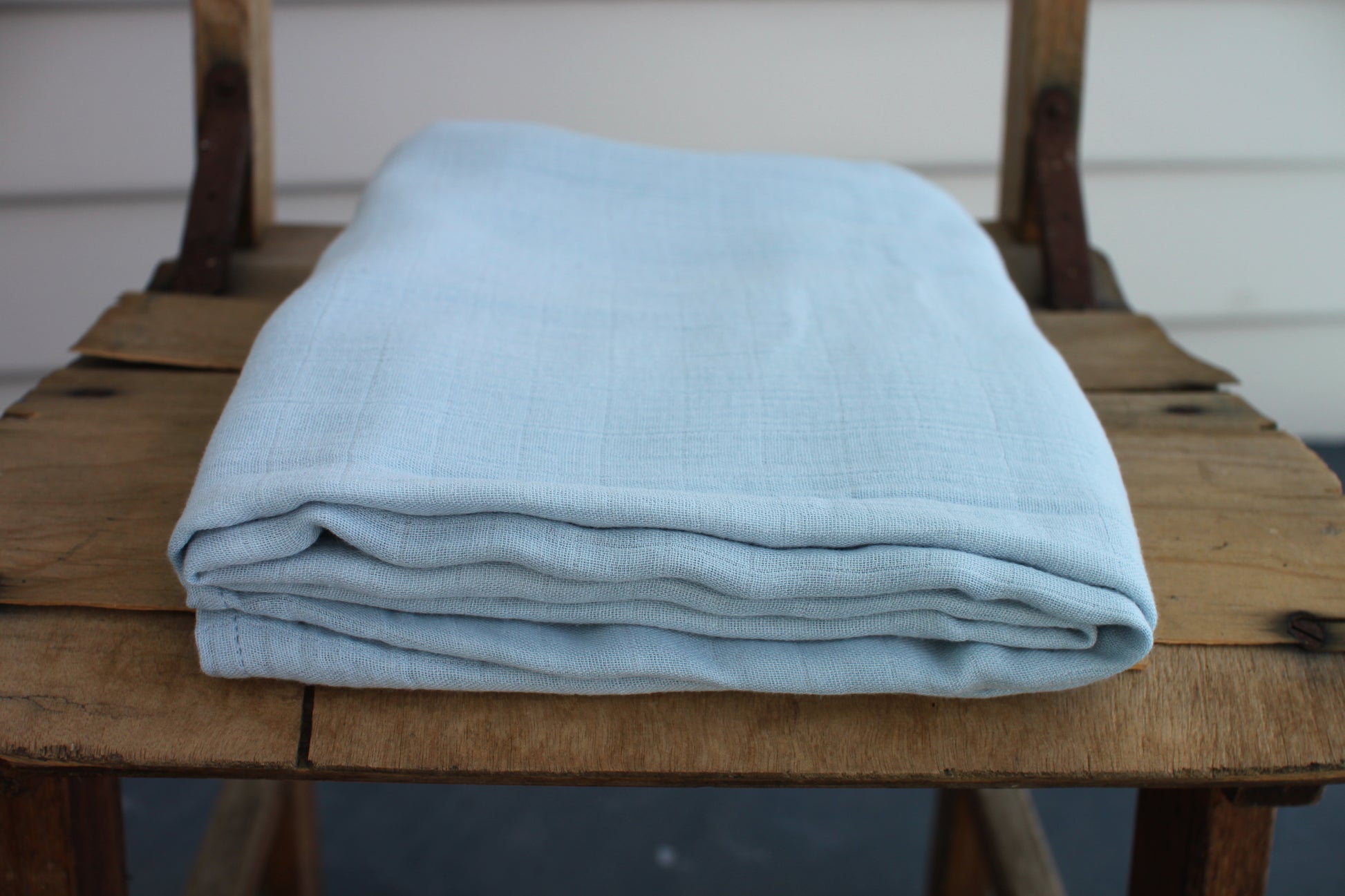 One sky blue muslin cloth sits folded on a wooden chair.