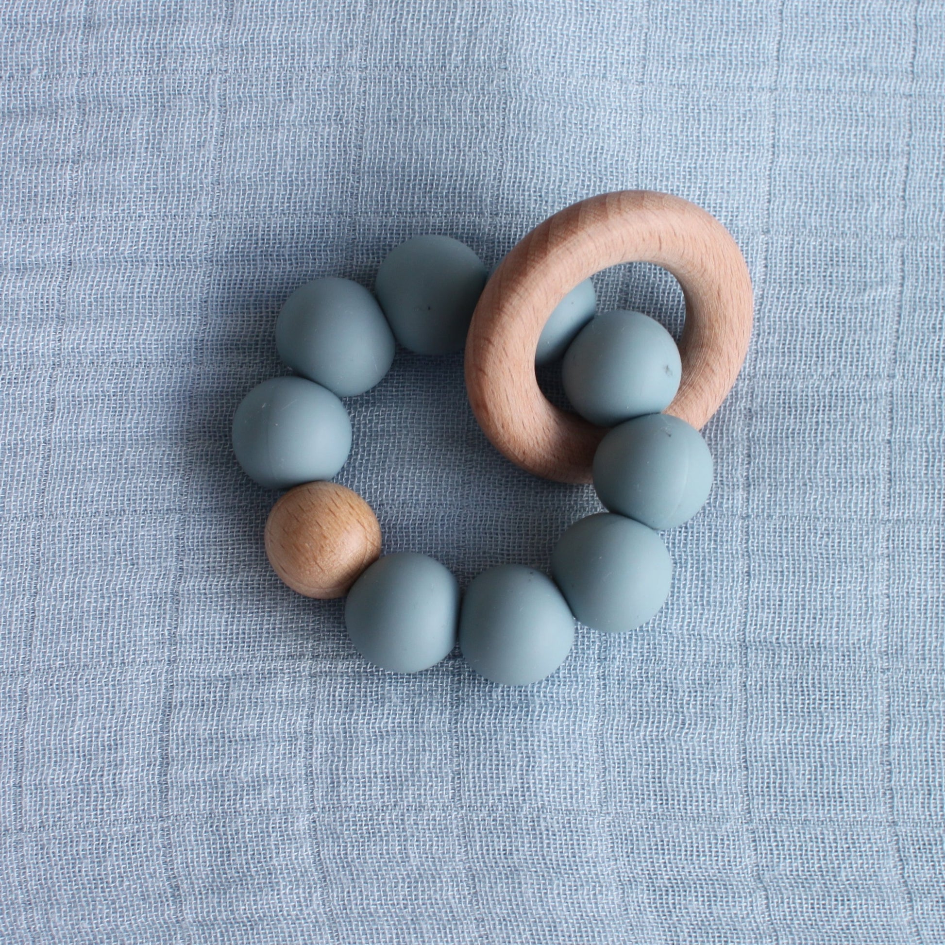 A silicone and beech wood teether. The silicone balls are blue. 