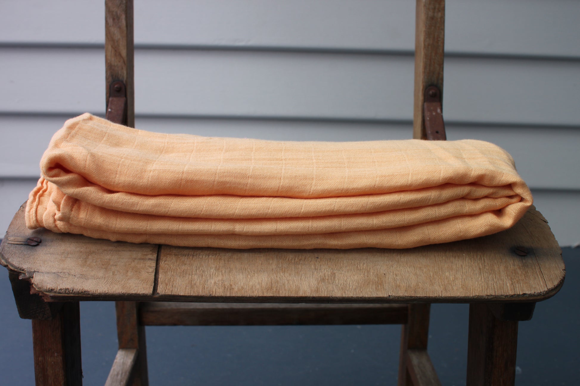 One orange muslin cloth sits folded on a wooden chair. 