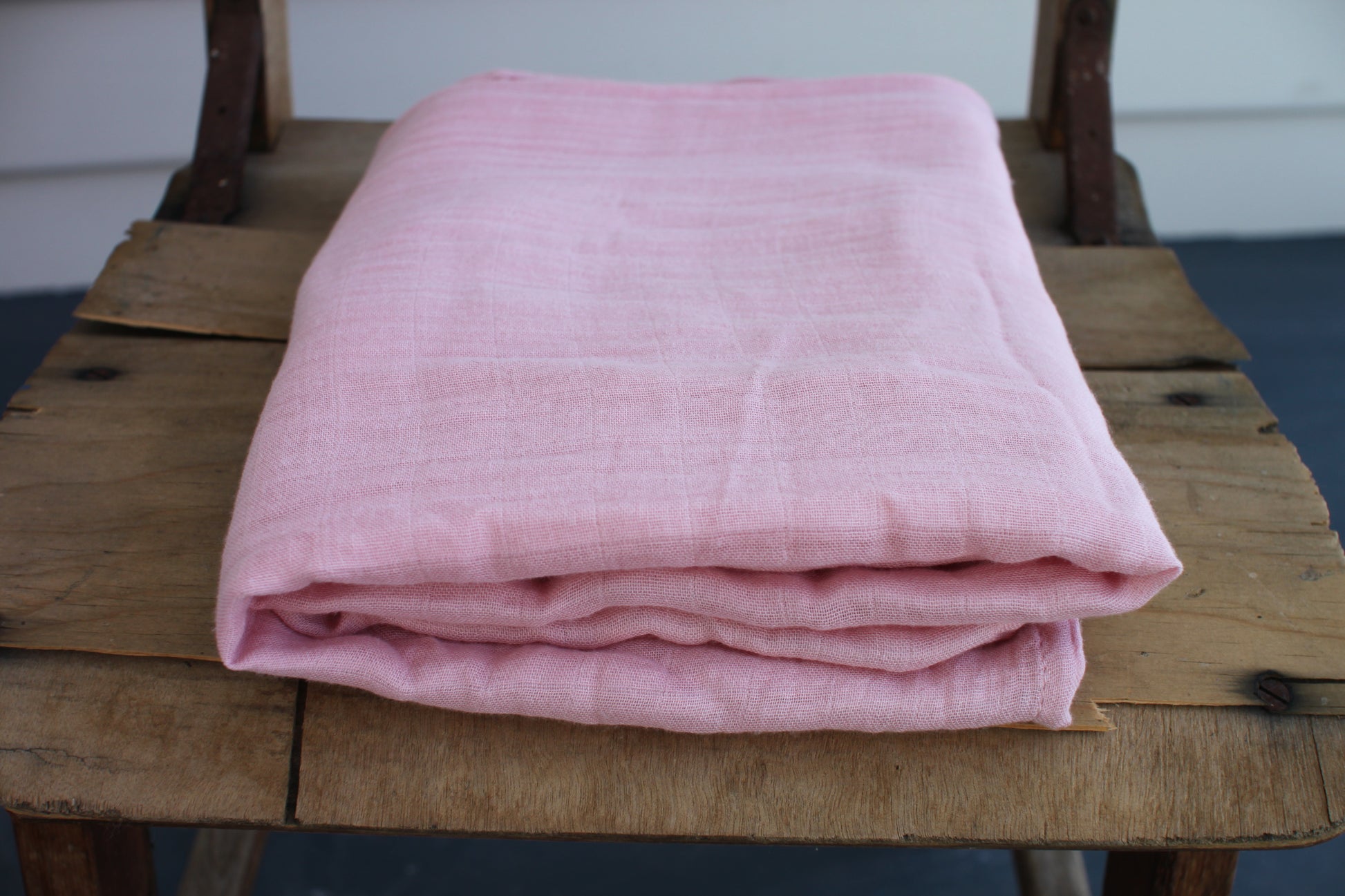 One pink muslin cloth sits folded on a wooden chair. 